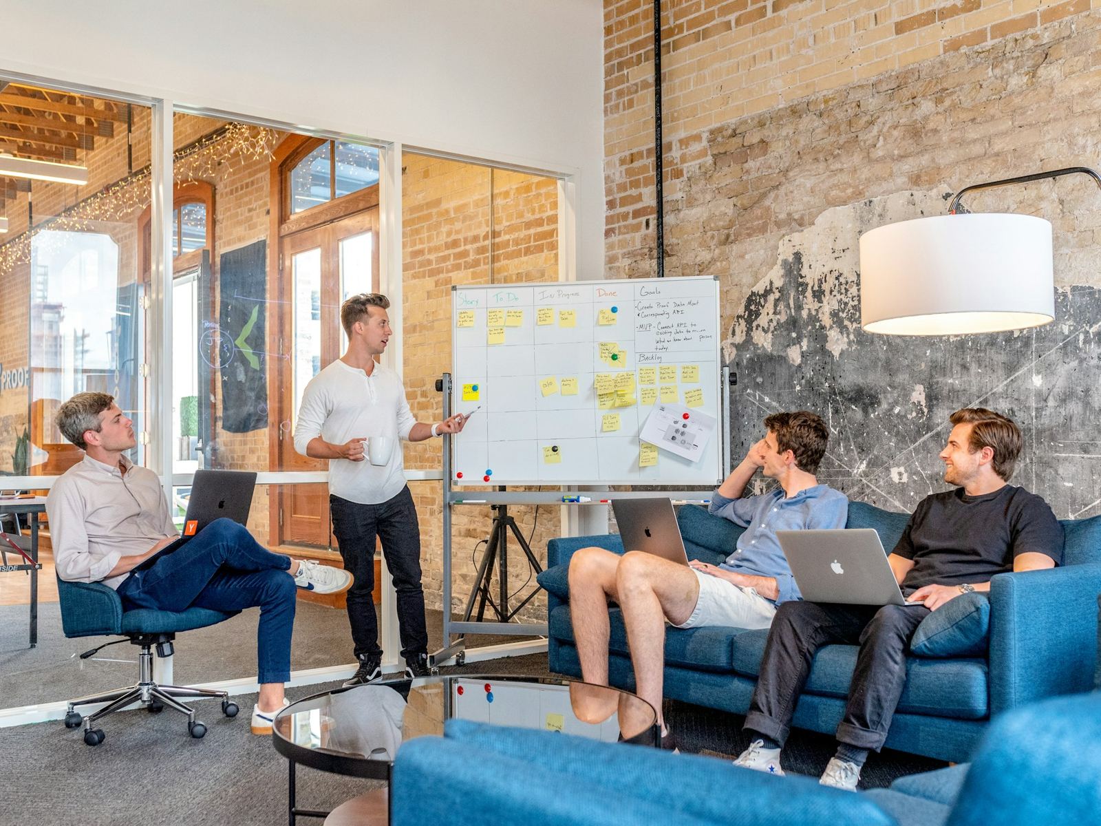 Colleague presenting a planning board with sticky notes to a team with laptops