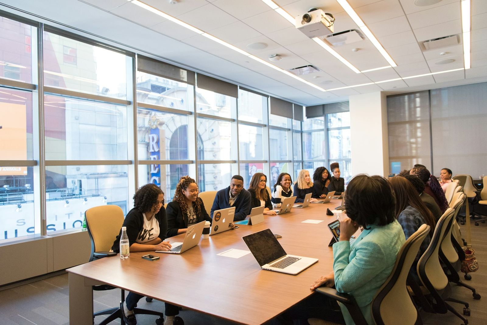 Team working with laptops around a long table in a bright office
